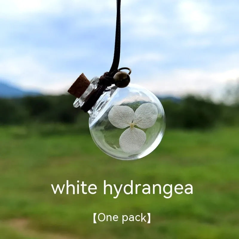Glass car perfume pendant with preserved flower decoration hanging in car interior