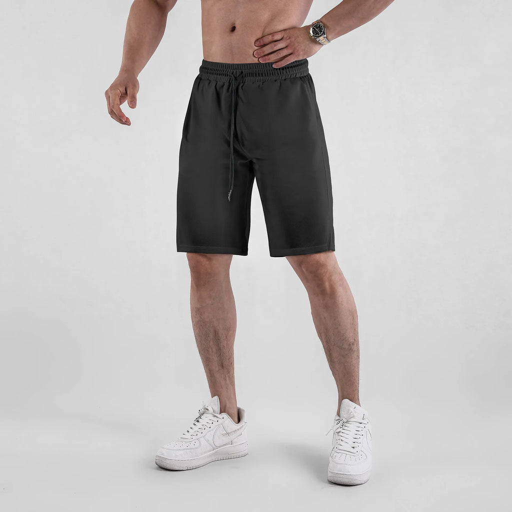 A man wearing loose-fitting black quick-dry mesh fitness shorts with an elastic waist.