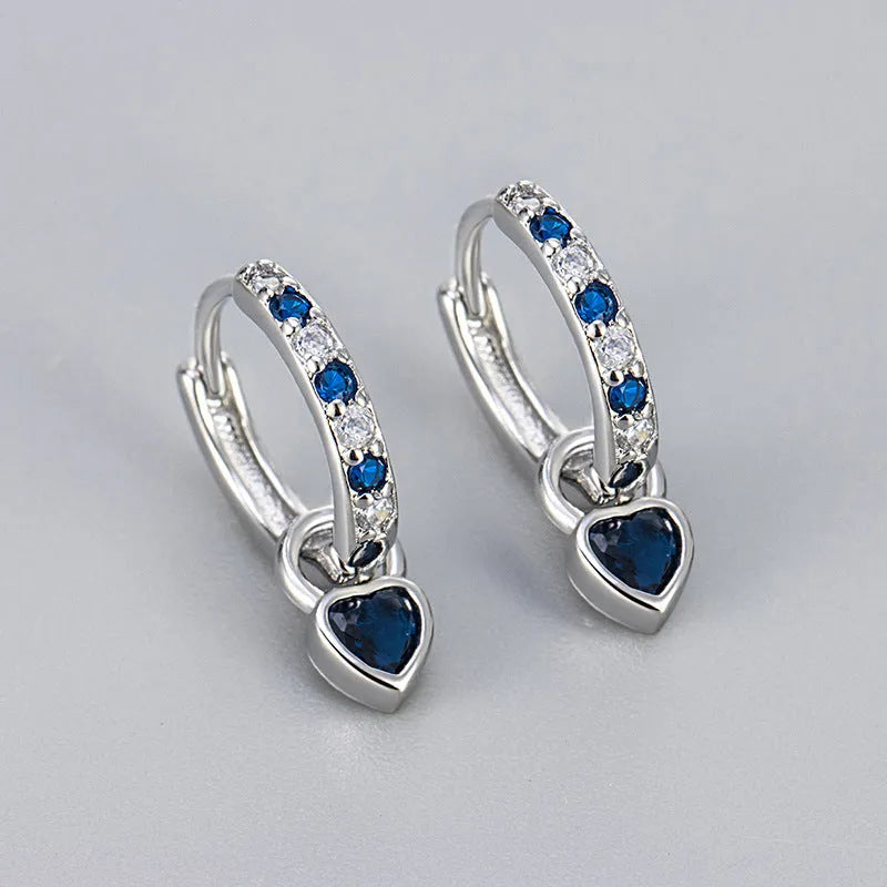 Gold colour heart-shaped clip earring with a central blue zircon stone on a white background.