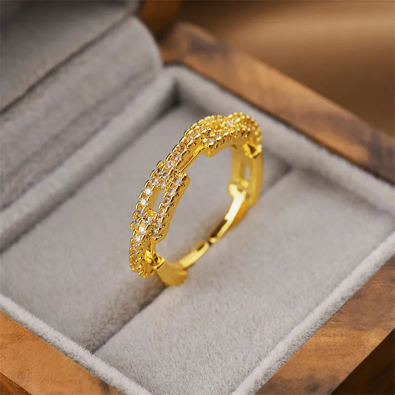 Gold electroplated geometric women's ring with an open adjustable design on a plain background