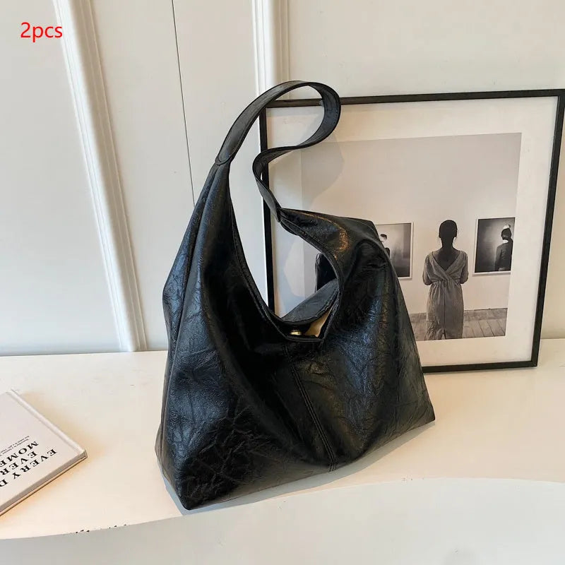 Soft black PU leather shoulder bag with large compartment and adjustable strap on a plain background.