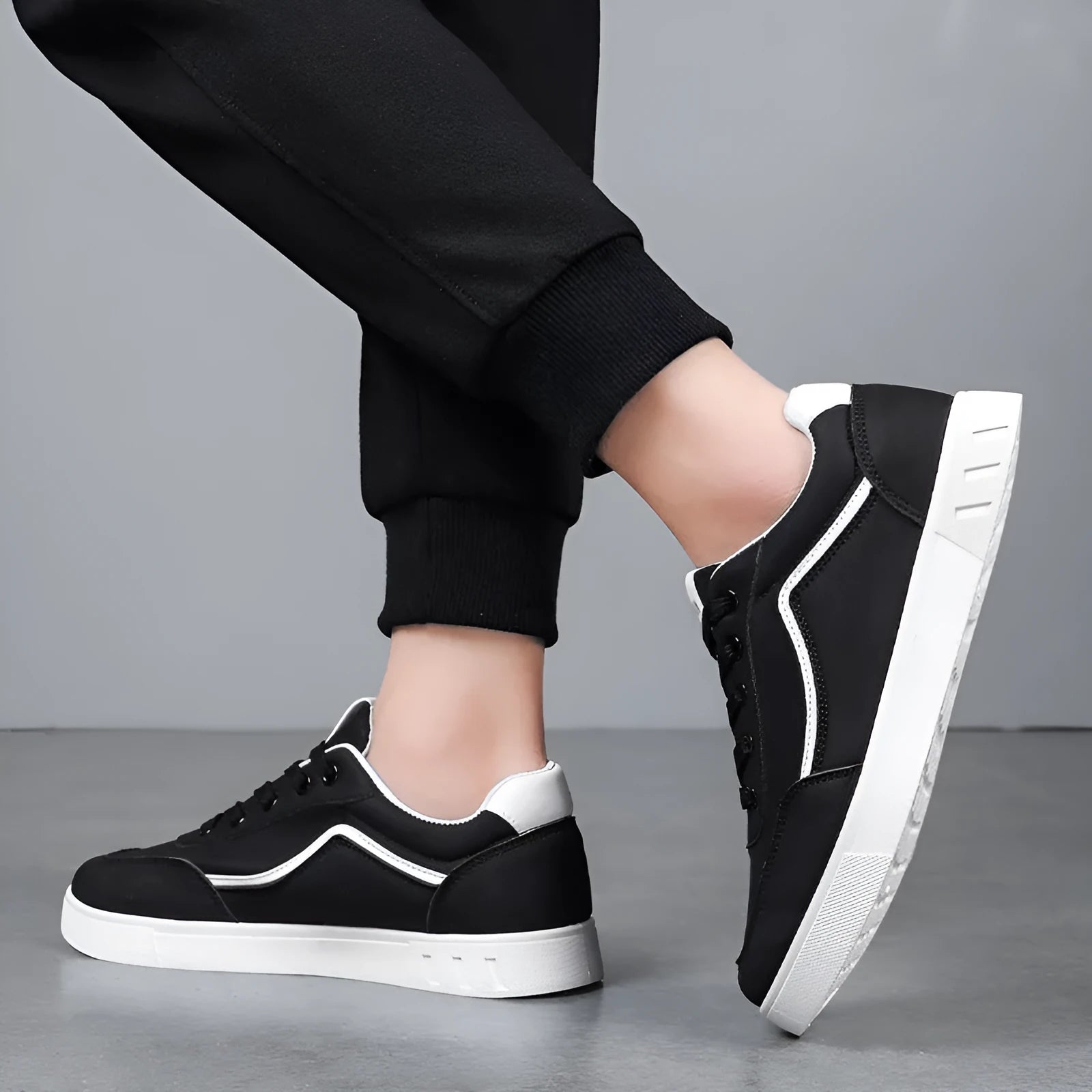 Men's low-top Korean style board sneakers in black with round toe, flat heel, and sewing line detail on the upper.