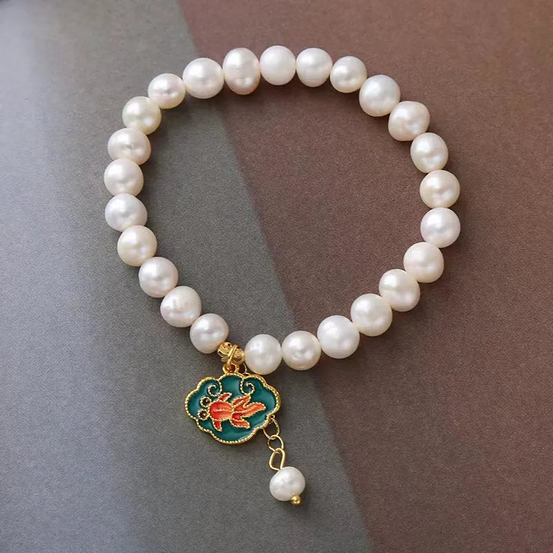 Natural freshwater pearl bracelet with vintage goldfish pendant and lotus motif on white background