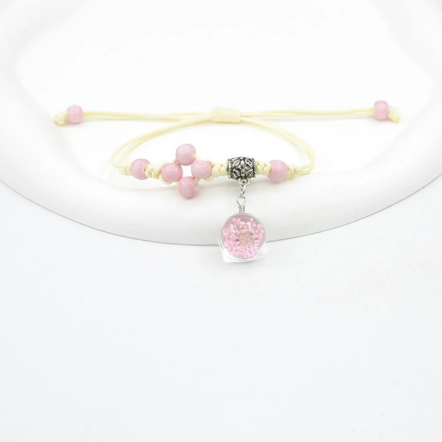 Close-up of a hand-woven glass bracelet with large 1.4cm beads containing real dried flowers in various colours.
