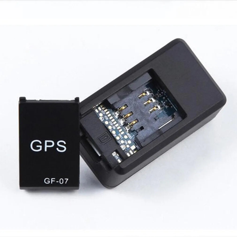 Small black plastic magnetic GPS tracker device next to a USB charging cable.