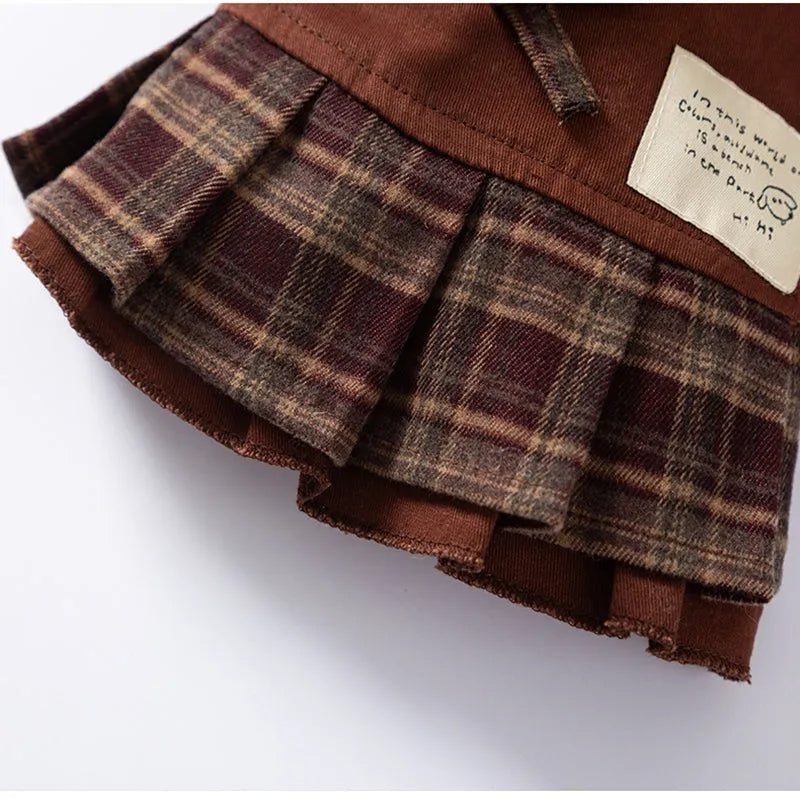 Fleece-lined brown plaid pet sweater dress with ruffle trim on a small dog, showing stretchable knit and skirt silhouette