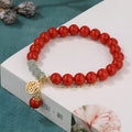 Close-up of a red cinnabar women's bracelet with a Fu character, jade spacer beads, and a small red tassel.