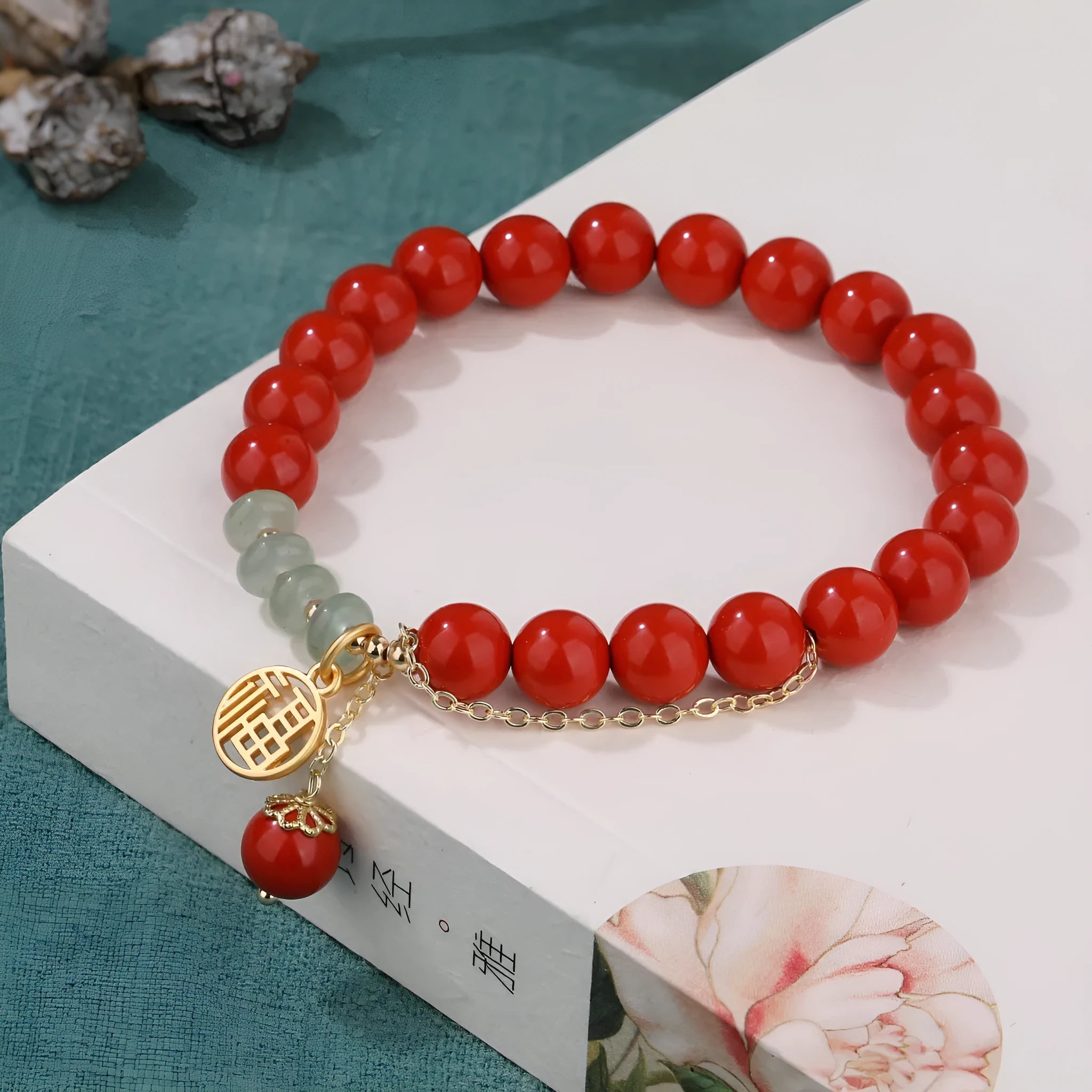 Close-up of a red cinnabar women's bracelet with a Fu character, jade spacer beads, and a small red tassel.