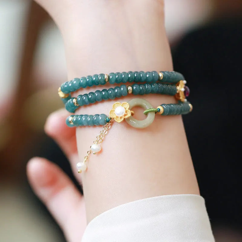 Blue water abacus and jade bead bracelet with tourmaline rings and pearl accents on a wrist.