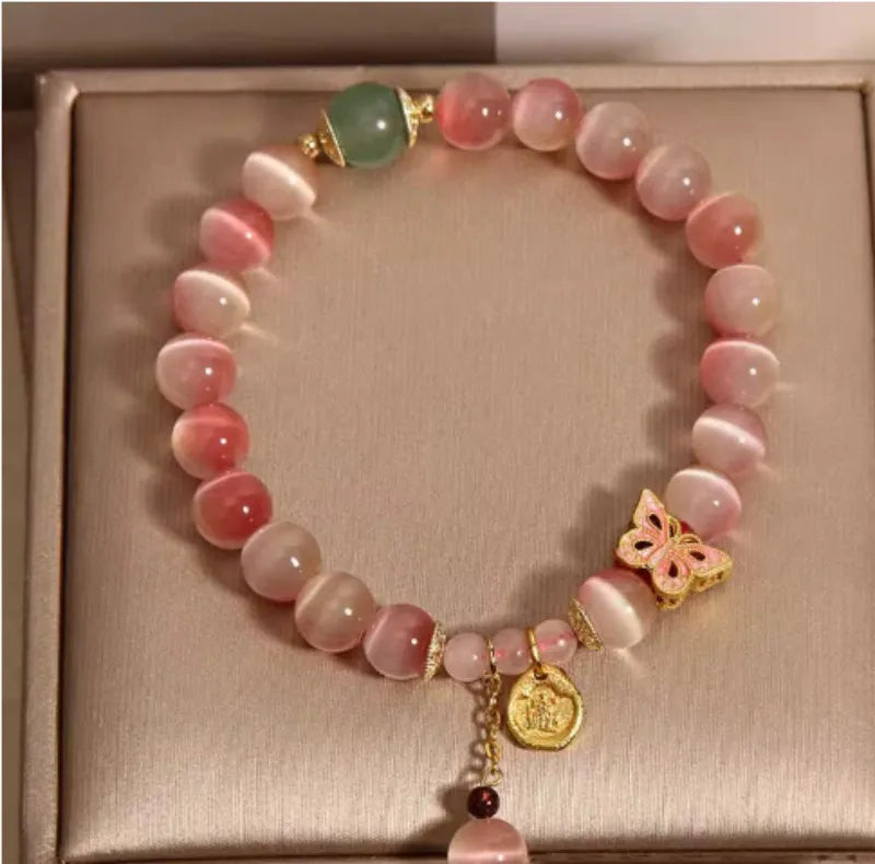 Close-up of a women's bracelet with a pink opal butterfly charm on an electroplated chain.
