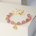 Close-up of a women's adjustable bracelet with pink strawberry quartz crystal beads and a silver fu charm on a geometric chain.