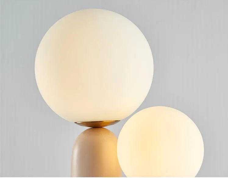 Pink double-head resin table lamp with glass shade on a bedside table, 49cm tall