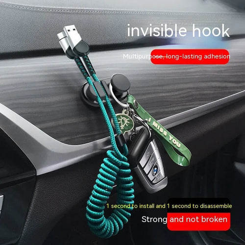 Dark green ABS silicone car cable hook with adhesive backing for organising data cables on a dashboard.
