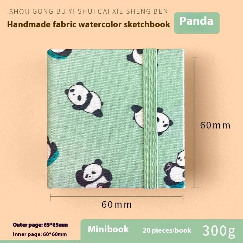 Feiluniao handmade fabric watercolour notebook with illustrated cover, open to show blank paper pages.