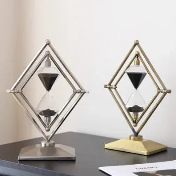 Glass sand clock timer with detailed metal ornaments in a bronze finish, showing modern simplicity style.