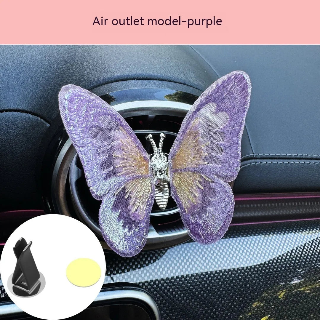Fabric embroidered butterfly car air vent decoration in multiple colour options on a dashboard.