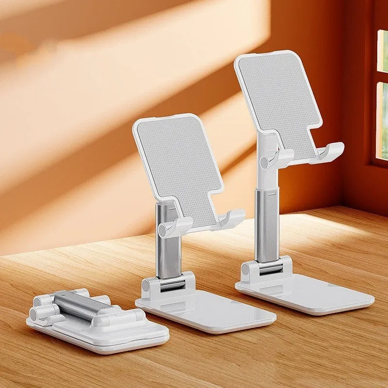 White folding telescopic mobile phone bracket holding a smartphone on a desktop.
