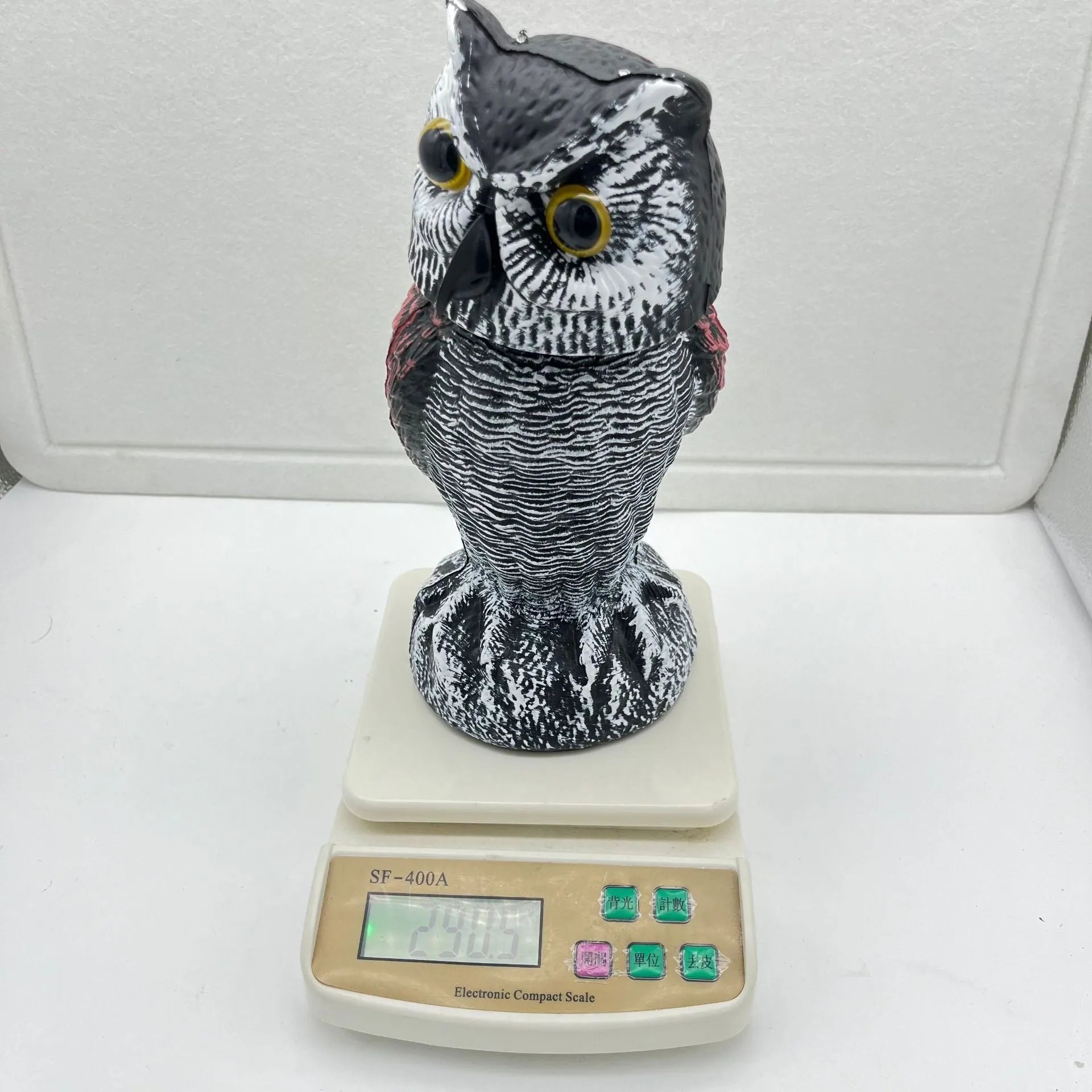 Artificial owl bird deterrent ornament with shaking head design in outdoor garden setting