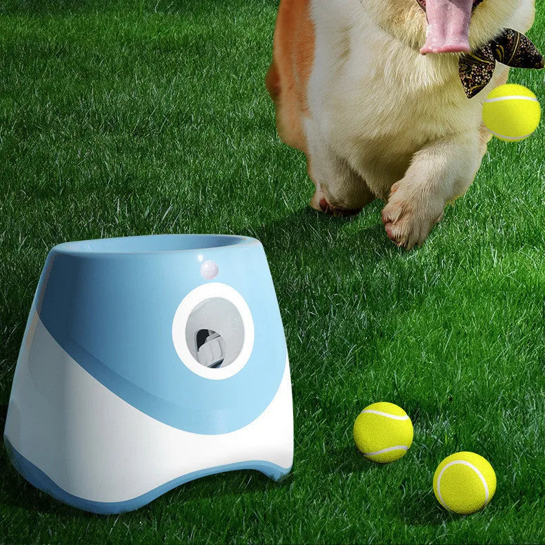 Blue automatic ball thrower with thermal sensor, three tennis balls, and USB charging cable on grass