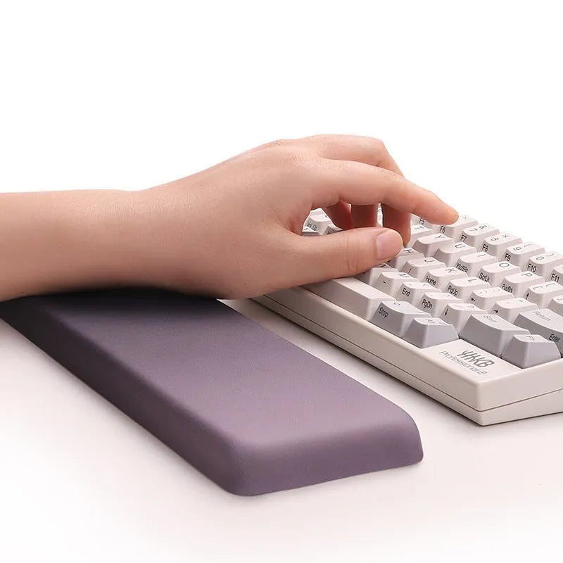 Square black silica gel wrist rest mouse pad on a desk, showing cloth surface and raised support pillow.