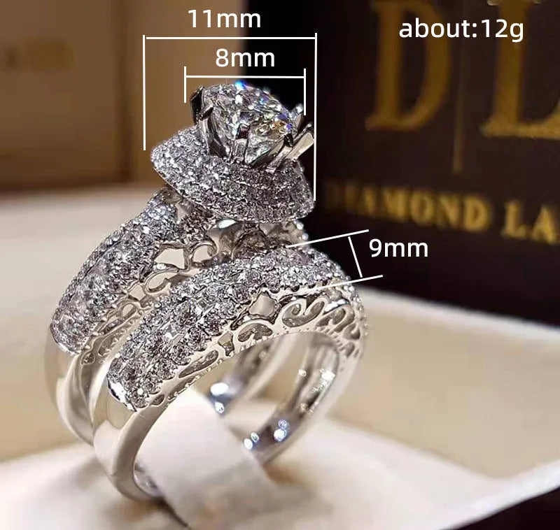 Pair of white gold colour copper couple rings with inlaid zircon stones, geometric U-shaped design on white background