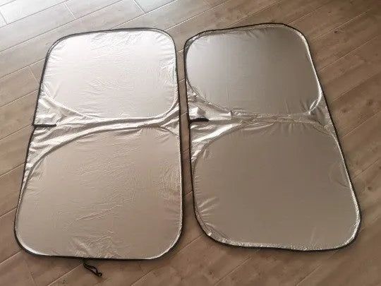 Titanium silver aluminium foil car windscreen sunshade unfolded on a dashboard.