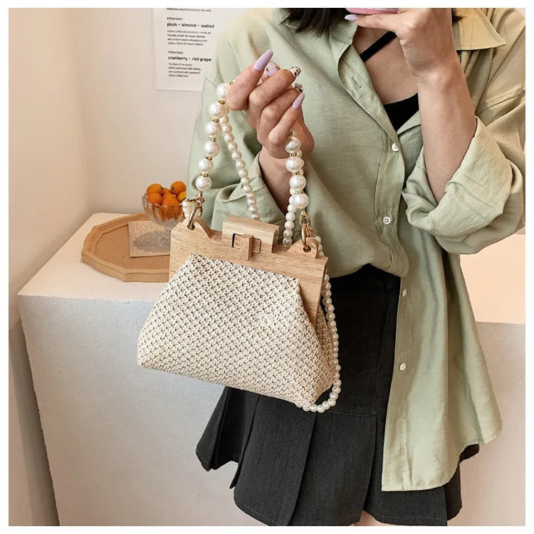 Women's straw woven shoulder bag with pearl chain strap showing interior organisation pockets