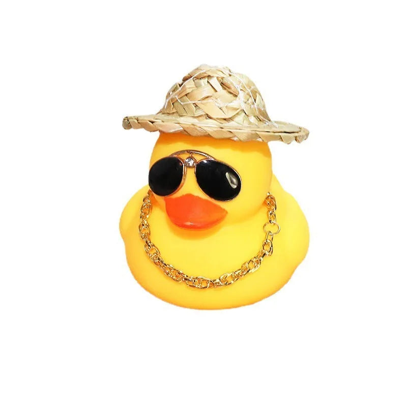 Yellow duck cartoon character wearing a straw hat, a car dashboard ornament with miniature sunglasses accessory.