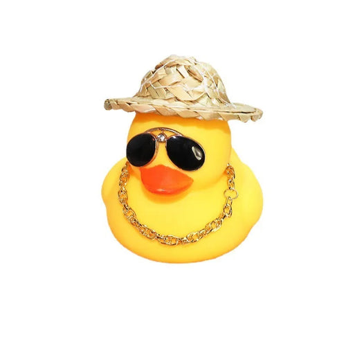 Yellow duck cartoon character wearing a straw hat, a car dashboard ornament with miniature sunglasses accessory.