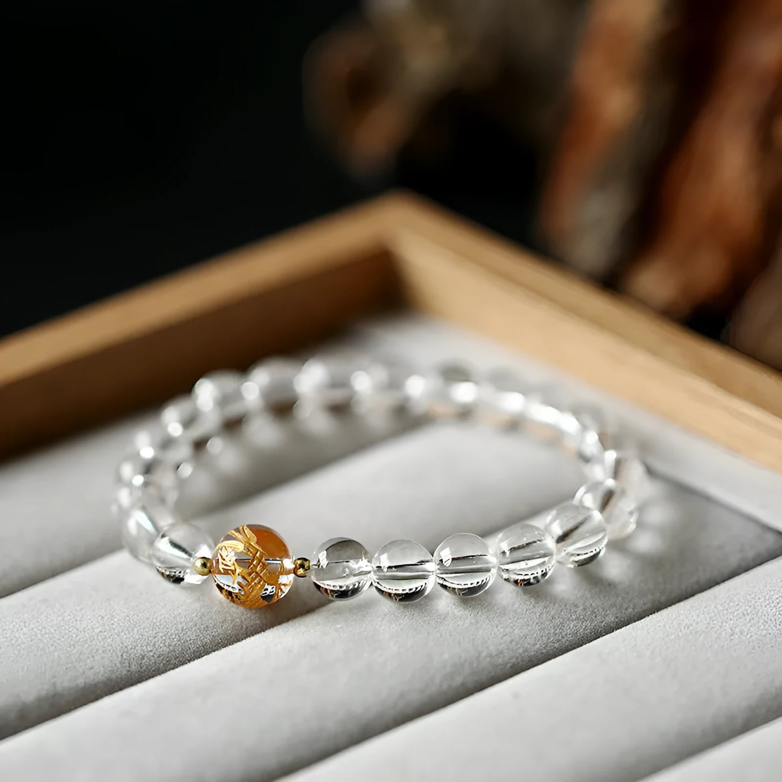 Geometric obsidian and white crystal bracelet with a golden dragon focal bead on a wrist.