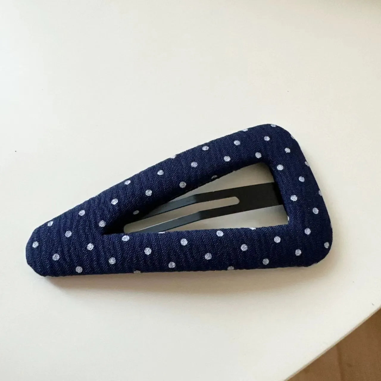Dark denim barrette with white polka dots in a triangle shape next to a water drop shaped barrette.