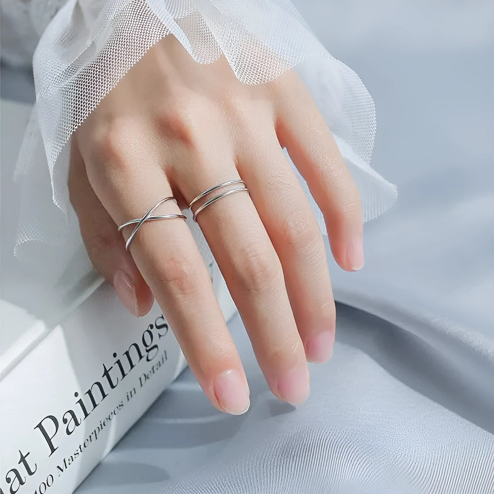 Silver plated geometric cross ring with adjustable opening on a plain background