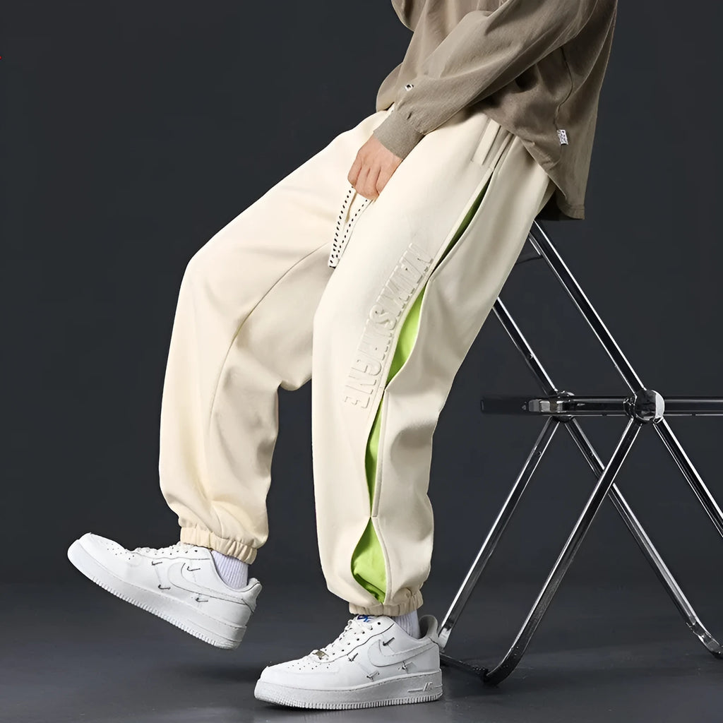 Men's loose fit cotton pants with elasticated ankle bands in grey green colour, showing collage stitching detail.