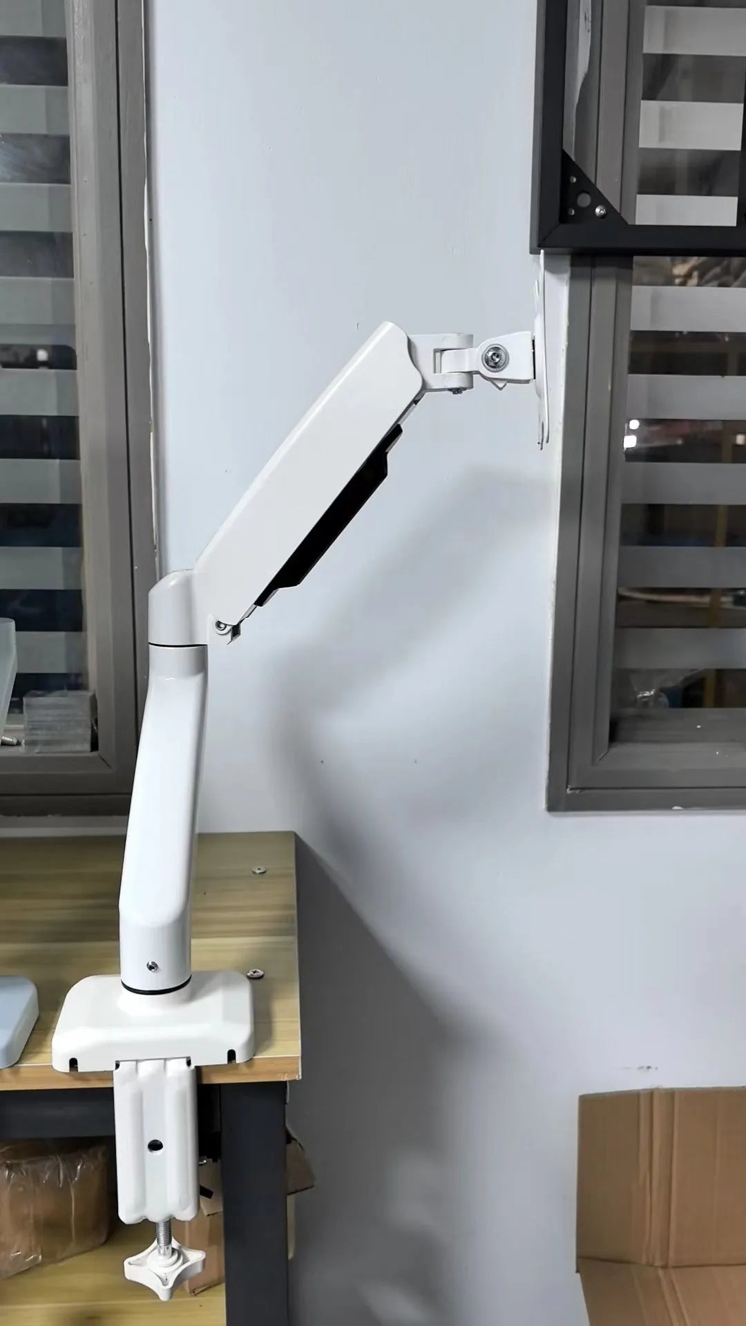 Black rotating telescopic monitor bracket on desk with adjustable arm and elevated design