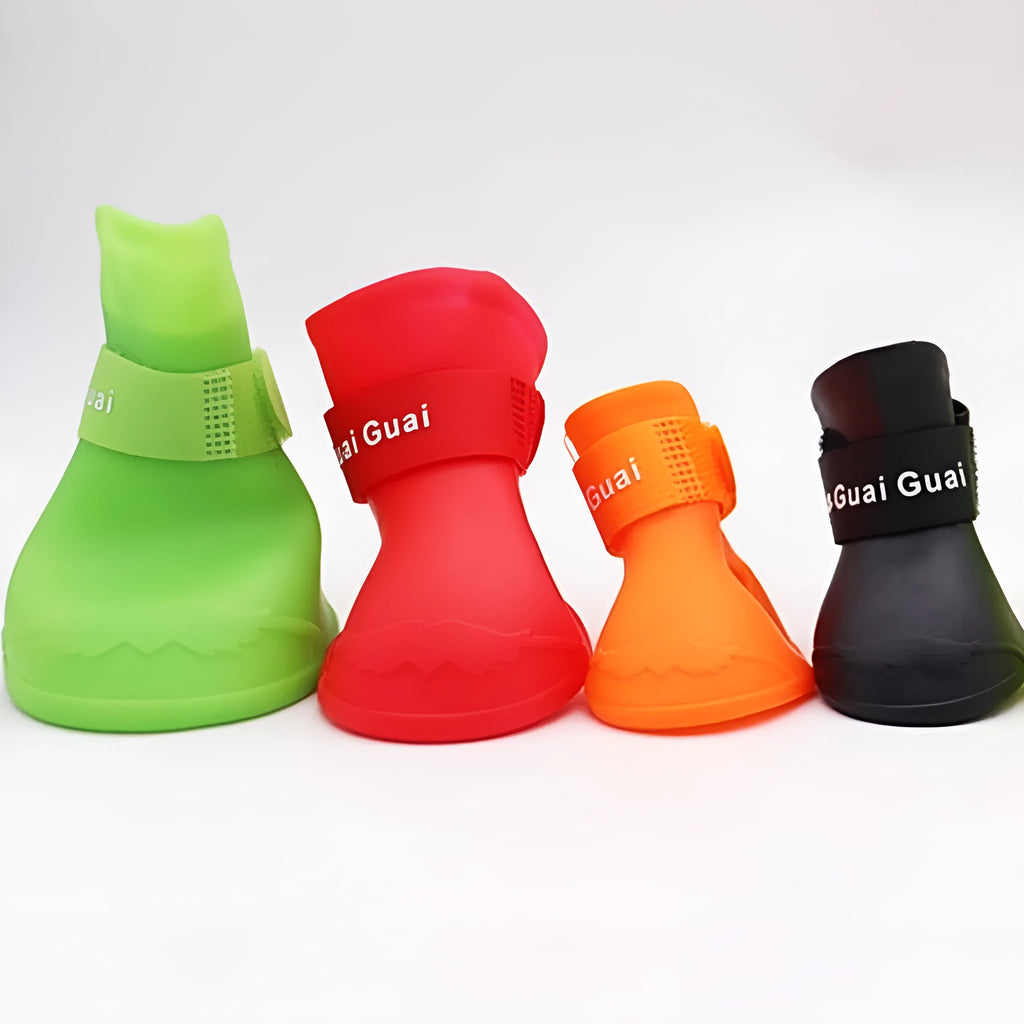 Set of four soft-soled rubber pet rain shoes in assorted colours on a grey background.