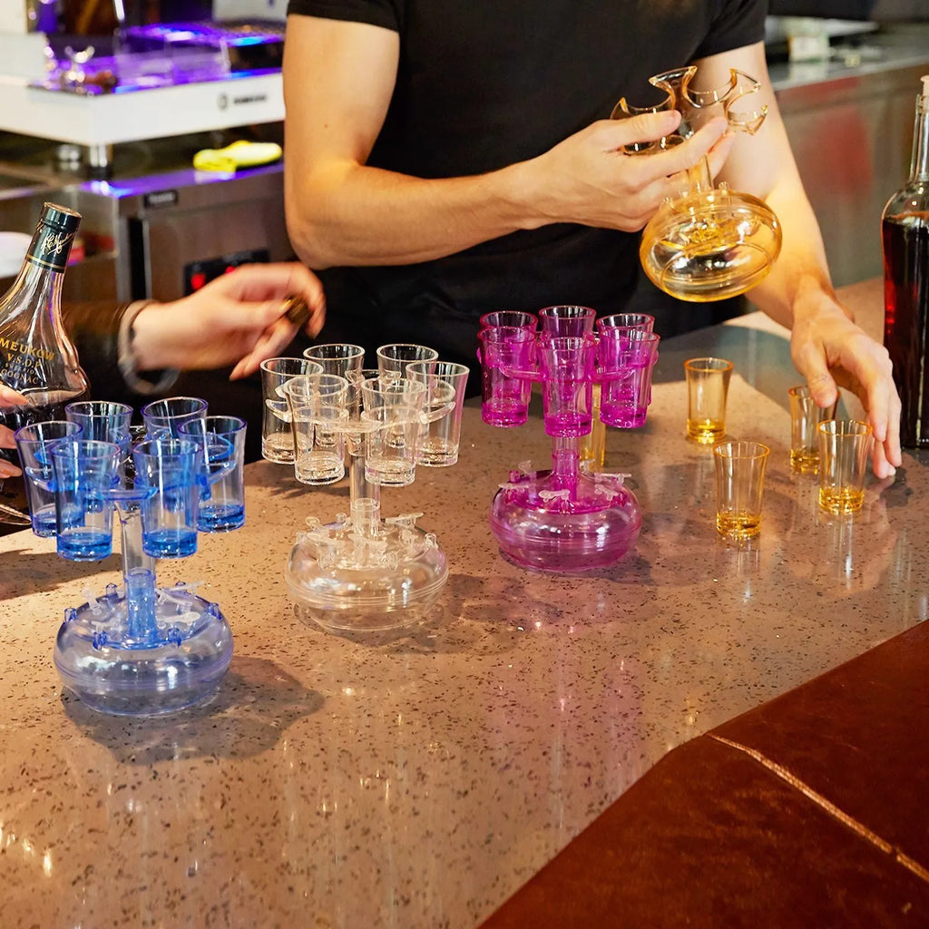 Clear PMMA 6-shot glass dispenser holder with rack and six cups on a table.