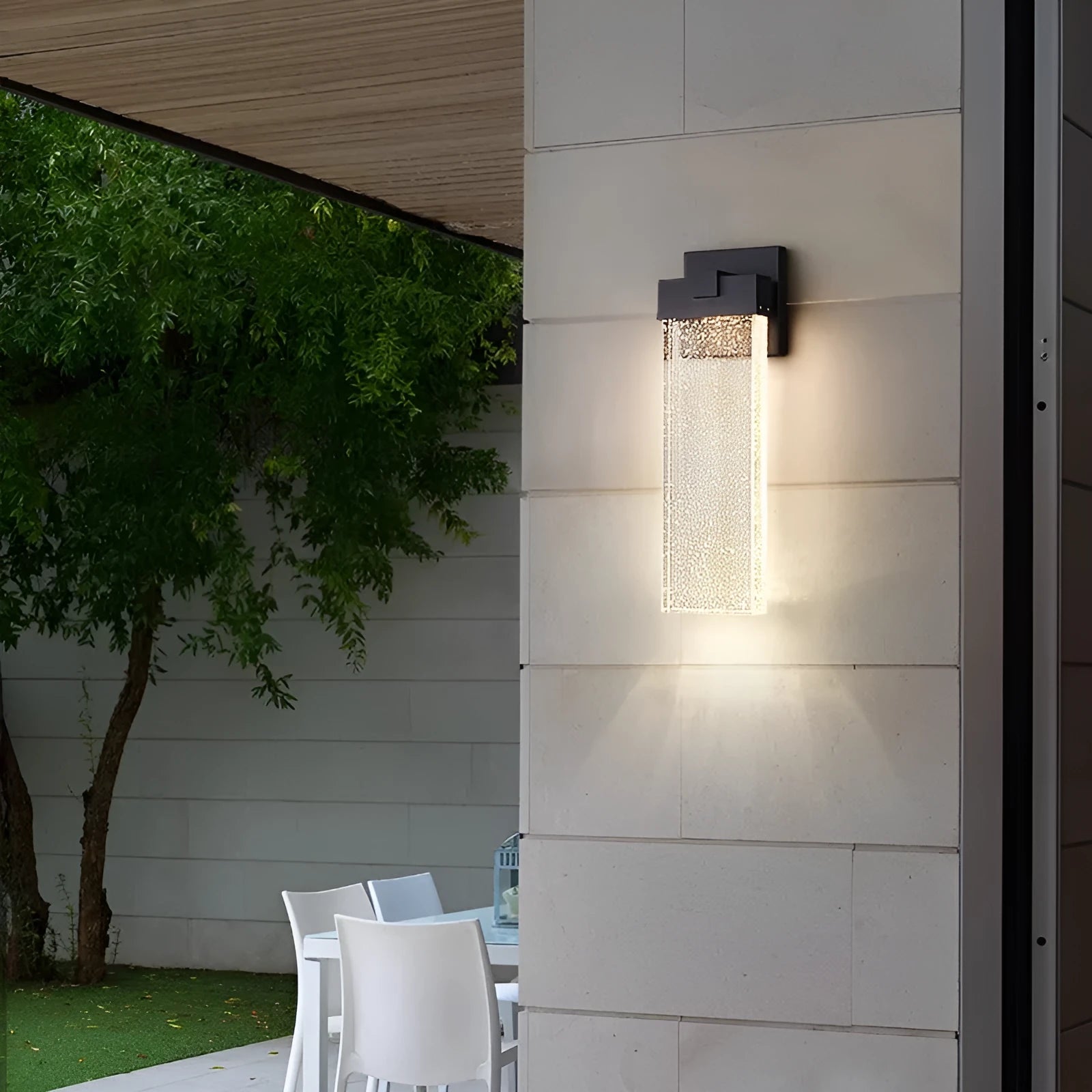 Black stainless steel outdoor LED wall lamp mounted on a wall, showing its rectangular shape and warm light emission.