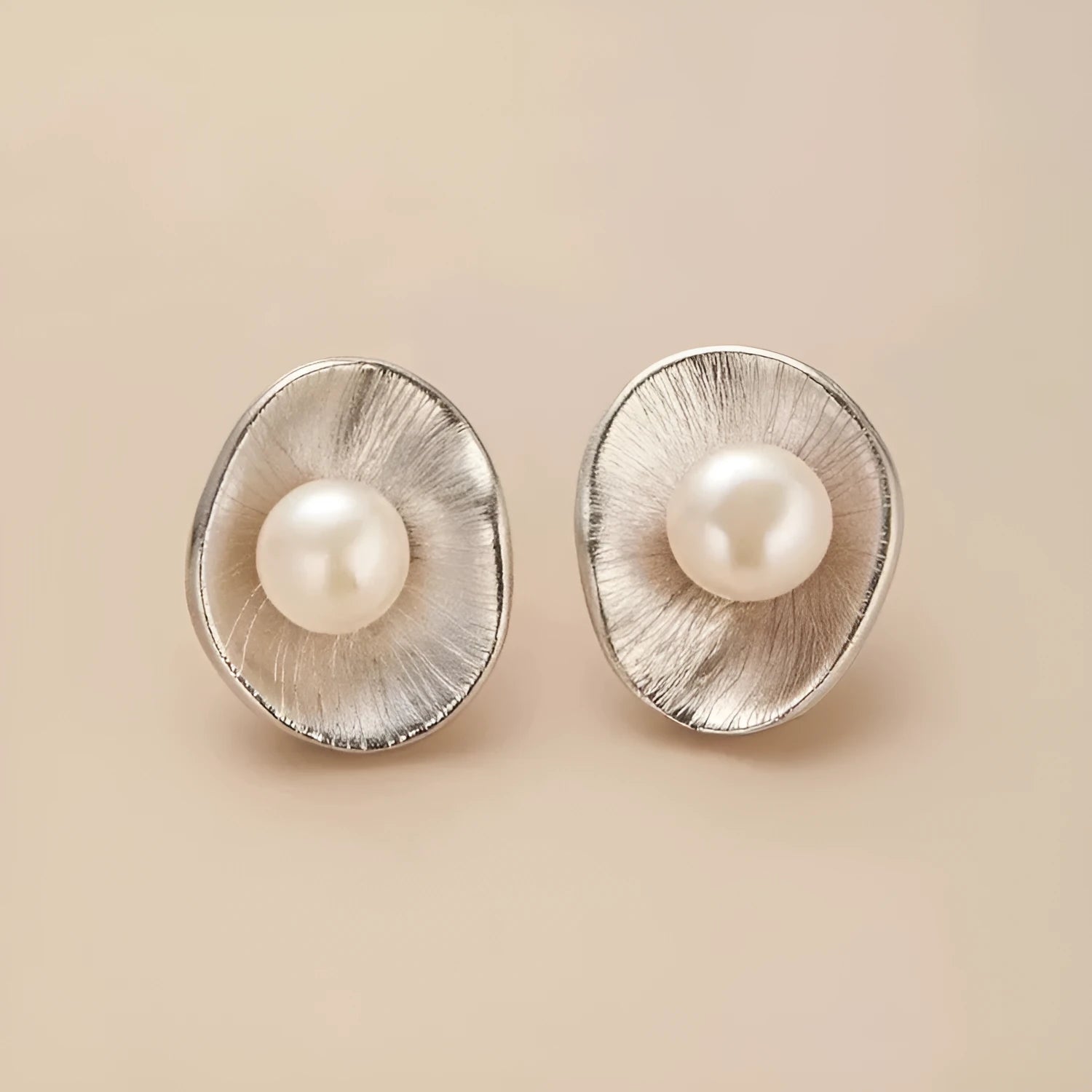 A pair of sterling silver geometric stud earrings featuring a central simulated pearl.
