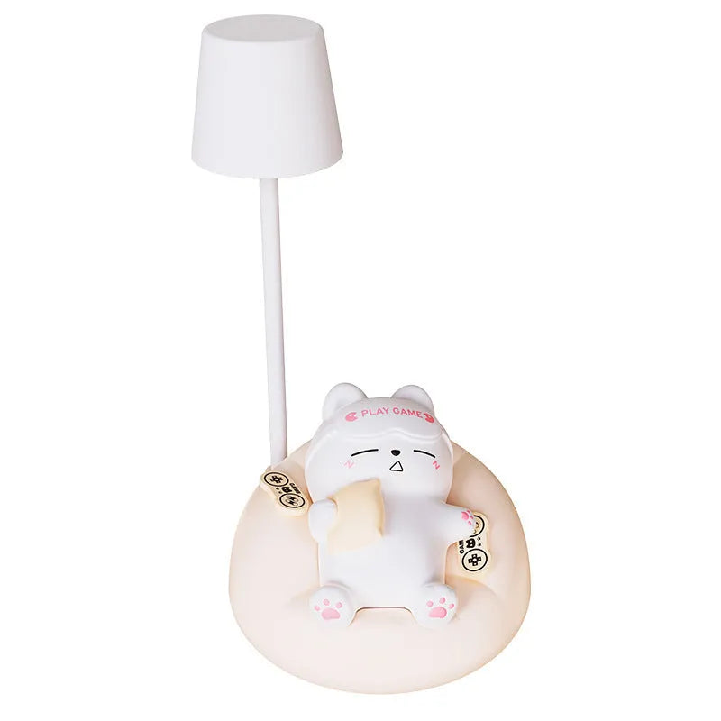 Sleeping cat shaped small night lamp in pink with USB charging cable on bedside table