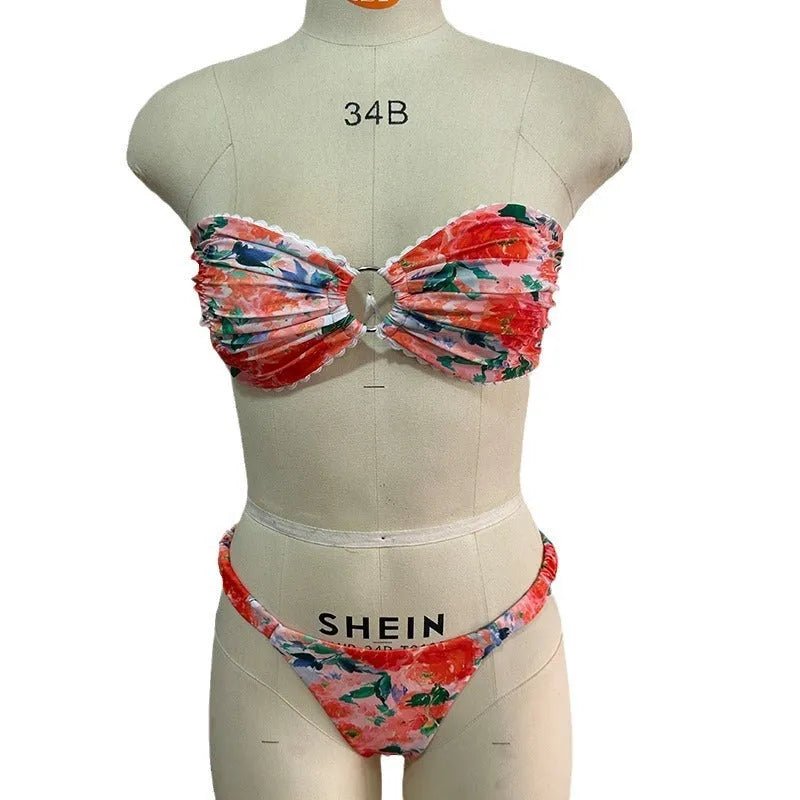 Women's floral print tube top bikini set with lace detailing on a blue background.